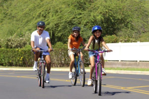 Family riding bikes down the street together
